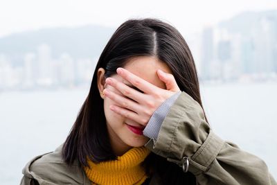Close-up of woman covering her eyes in city