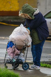 Full length of person with shopping cart on footpath