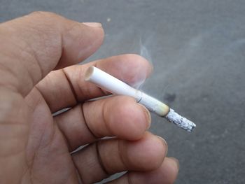 Cropped image of hand holding cigarette