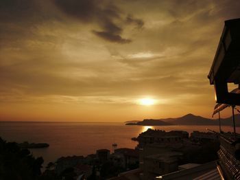 Scenic view of sea and buildings against sky during sunset