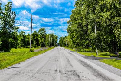 Road amidst trees against sky