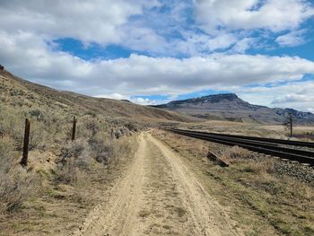 Scenic view of road leading towards mountains against sky