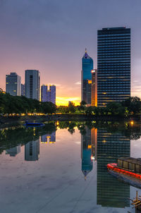 Illuminated buildings in city against sky during sunset