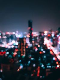 Defocused image of illuminated city against sky at night