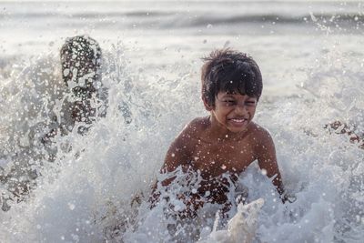 Portrait of shirtless boy splashing water