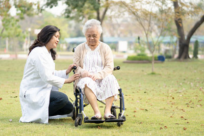 Doctor consoling senior woman sitting on wheelchair at park