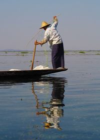 Man fishing in sea against sky