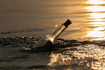 Message in a bottle in gently moving water at sunset