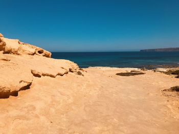 Scenic view of beach against clear blue sky
