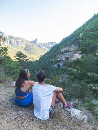 Rear view of people sitting against mountain