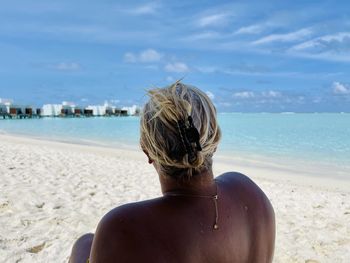 Rear view of man on beach against sky