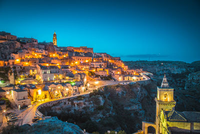 Illuminated townscape against clear blue sky at dusk