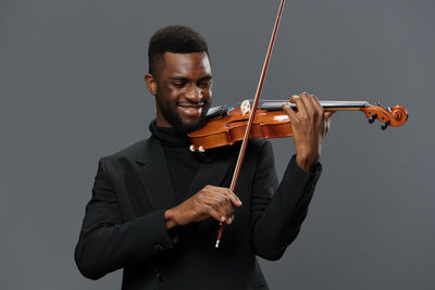 Man playing violin against black background