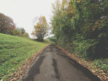 Road amidst trees against clear sky