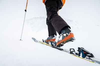 Close-up of the legs. winter skitour freeride in cloudy weather, snow-capped mountains against the