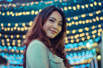 Close-up portrait of young woman amidst illuminated lights