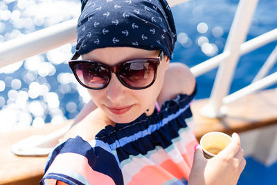 High angle view of woman wearing sunglasses sitting by railing in boat