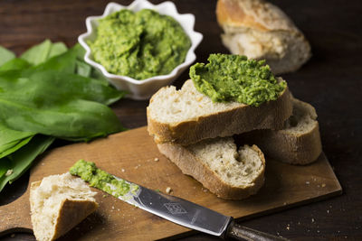 Close-up of bread with green paste and leaves on wooden table