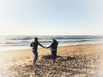 People on beach against clear sky