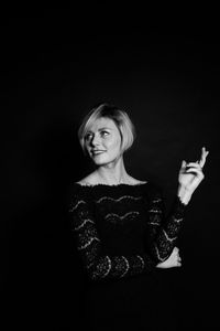 Portrait of smiling woman against black background