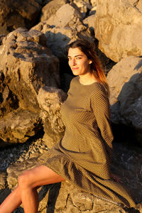 Young woman looking away while standing on rock