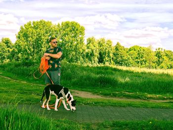 Woman with dog on field against sky