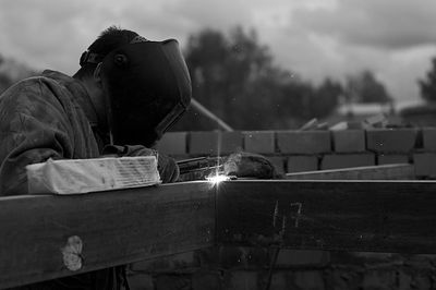 Man welding while standing against sky