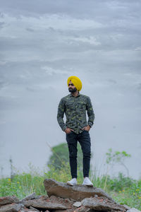 Man standing on rock against sky