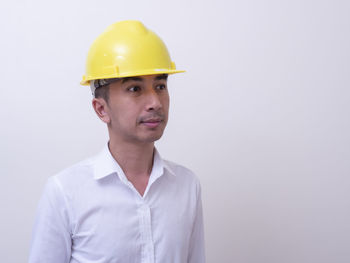 Portrait of mid adult man wearing hat standing against white background