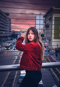 Portrait of beautiful young woman standing against building in city