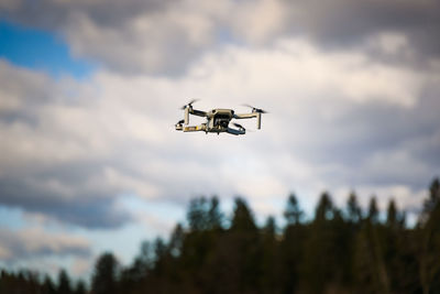 Low angle view of drone flying against sky