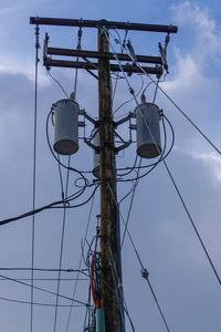 Low angle view of electricity pylon against sky