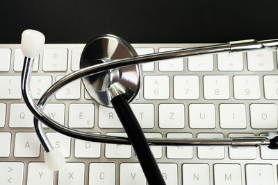 Directly above shot of stethoscope and computer keyboard against black background