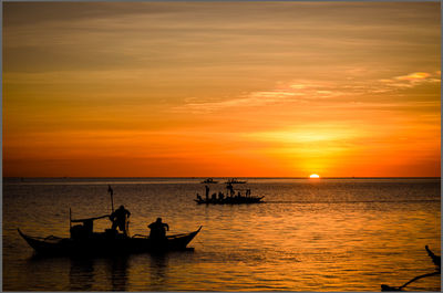 Silhouette people on boat sailing in sea during sunset