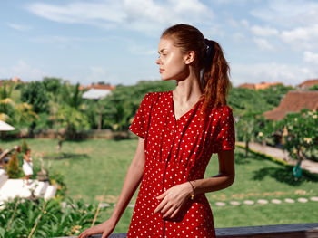 Young woman standing against trees