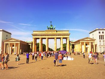 People at brandenburg gate against sky on sunny day