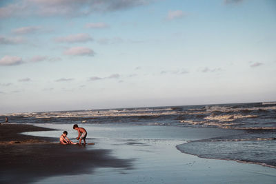 Full length of kids playing on beach against sky