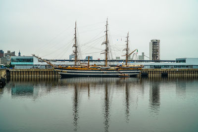 Boats moored at harbor against sky