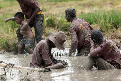 Men and boy playing in mud at field