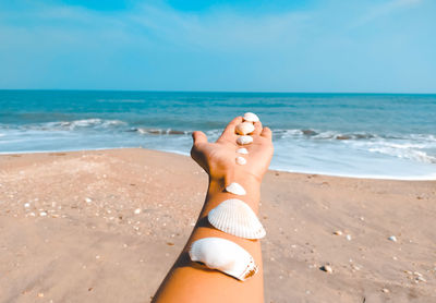 Low section of person on beach against sky