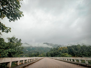 Road amidst trees against sky