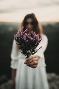 Midsection of woman holding purple flowering plant