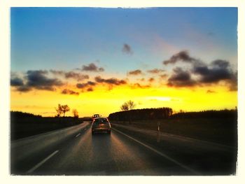 Road passing through landscape at sunset