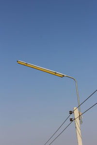 Low angle view of electricity pylon against clear blue sky