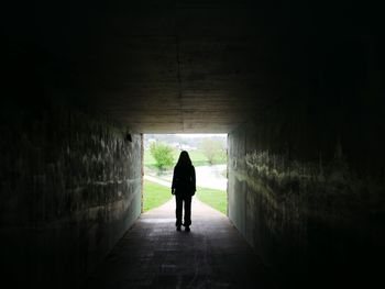 Rear view of woman walking in tunnel