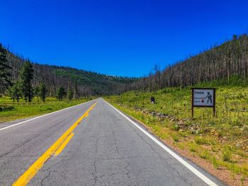 Empty road against clear blue sky