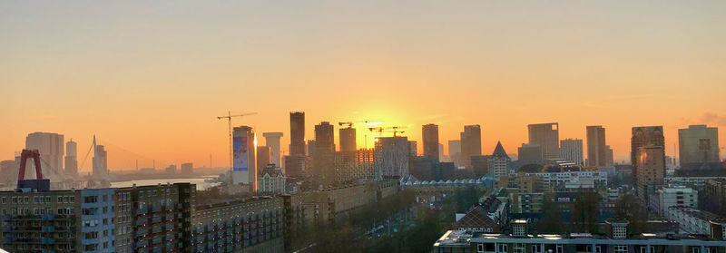 Modern buildings in city against sky during sunset