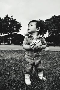 Cute boy holding ball while standing on field