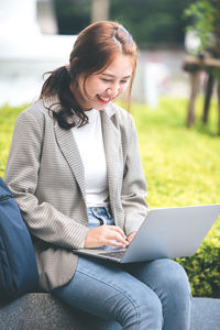 Young woman using laptop while sitting outdoors
