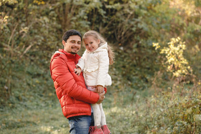 Portrait of father with daughter standing in forest